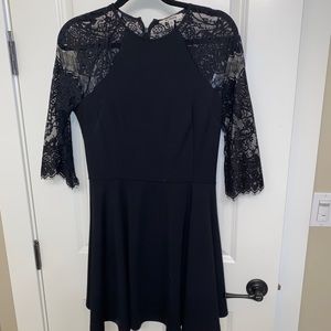 Flowy black dress with solid core and lacey shoulders, arm, and back.